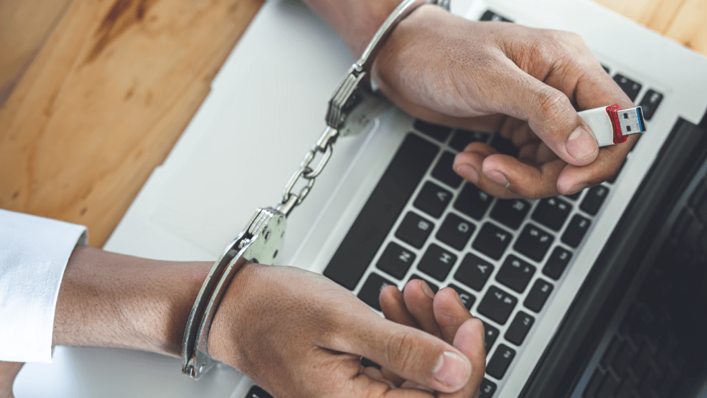 a person in handcuffs holding a laptop computer