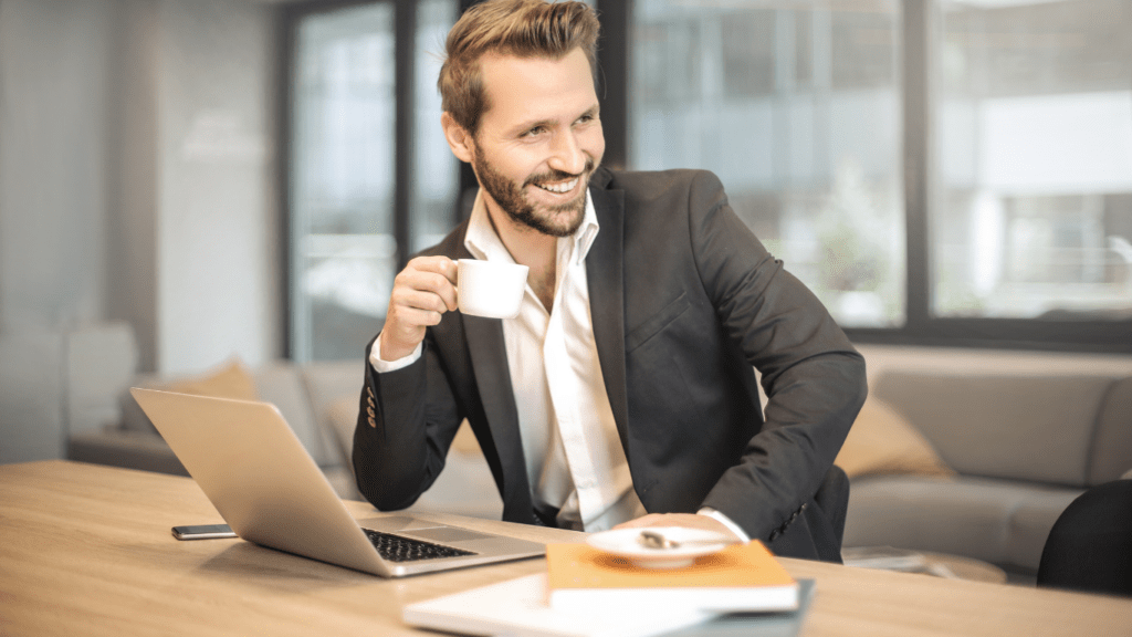 a person sitting in front of laptop with a cup of coffee