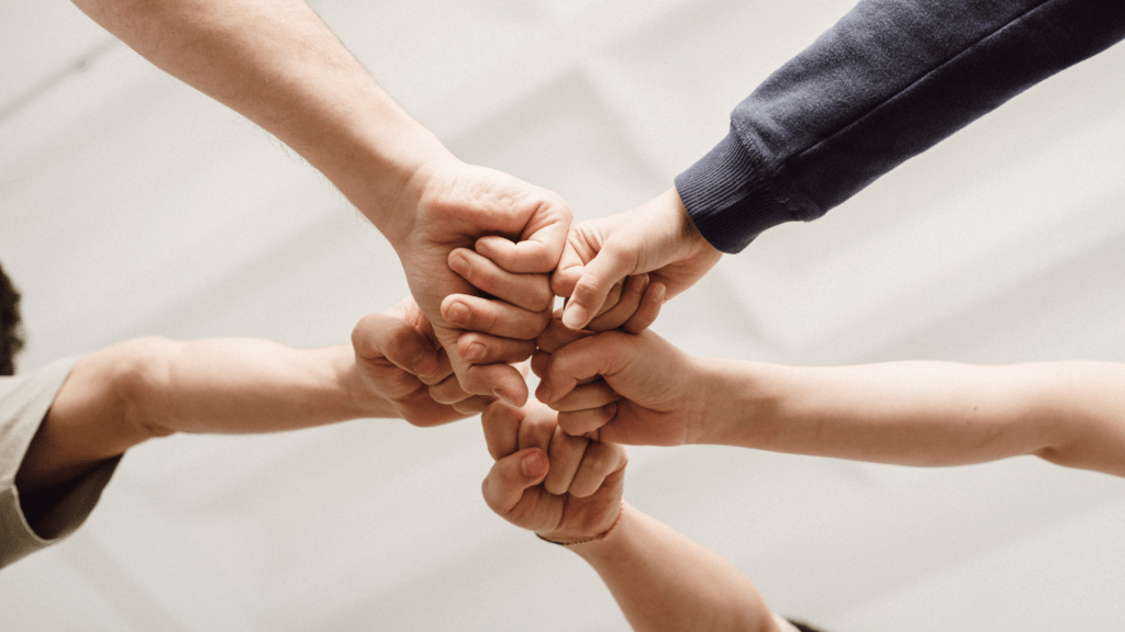 a group of people holding their hands together in a circle