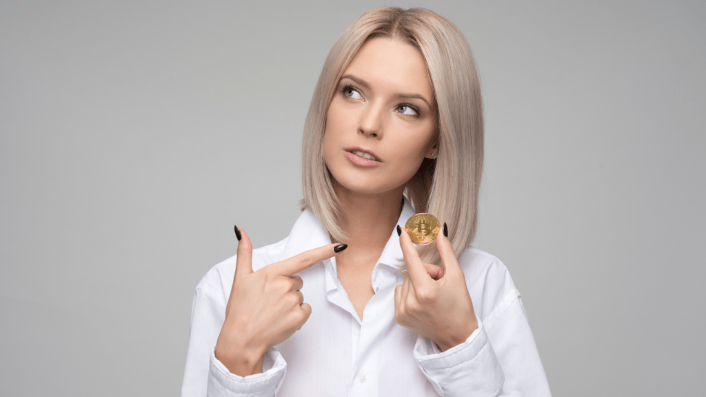 a person in a white shirt is holding up a gold coin