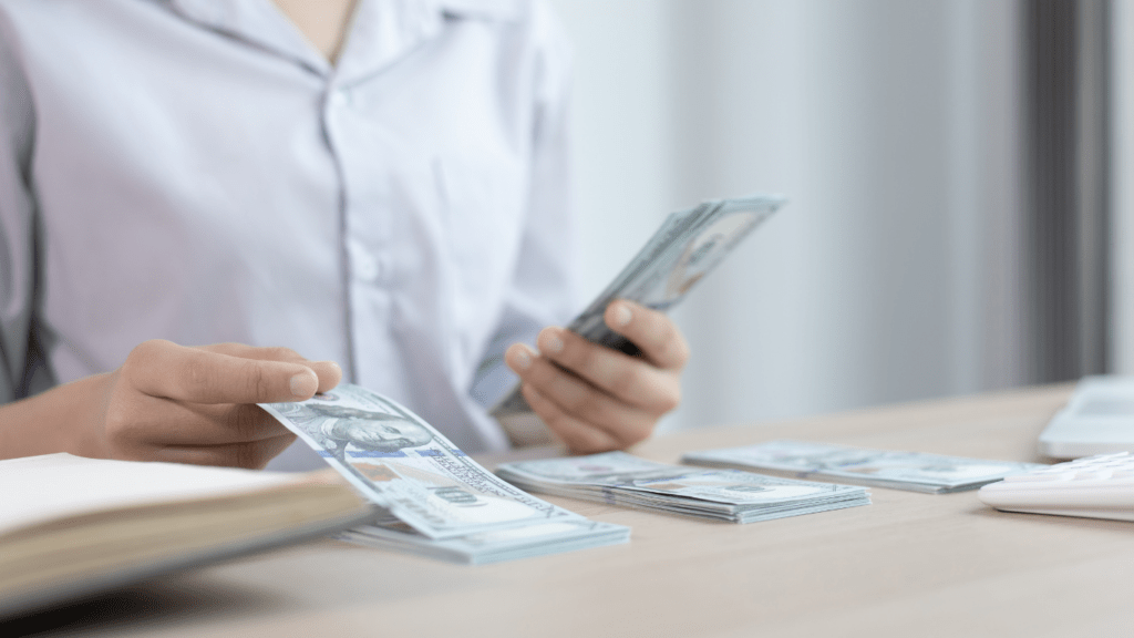 a person is counting money in front of a laptop