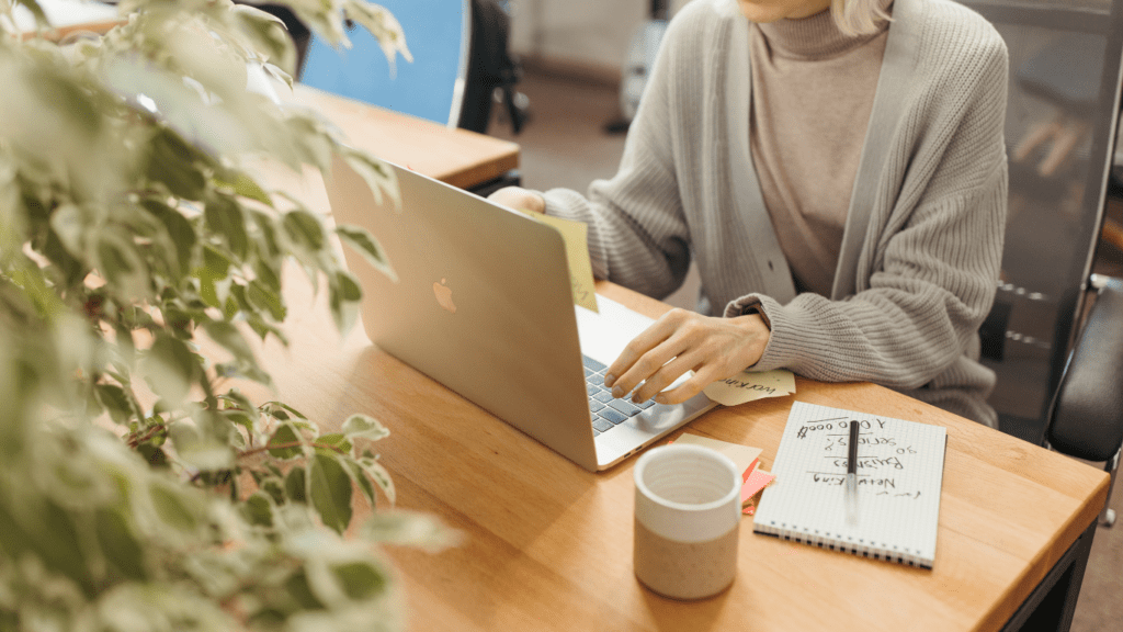 a person sitting in front of laptop with a cup of coffee