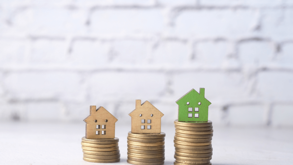 a stack of coins with miniature houses sitting on top of them