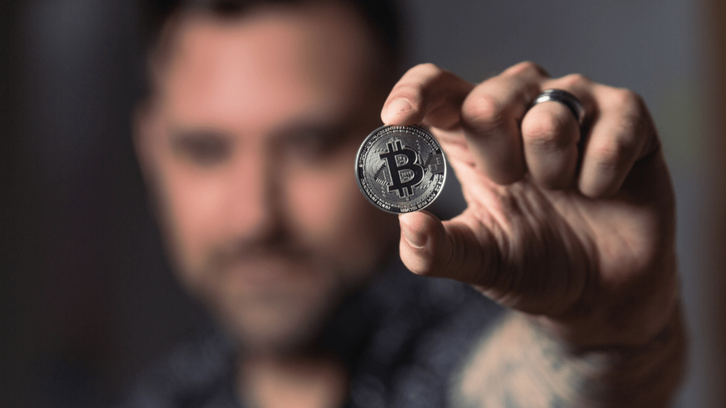 A man holding silver bitcoin coin