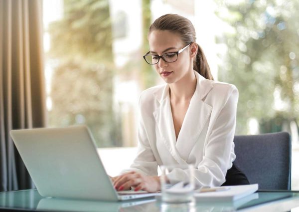 Concentrated female entrepreneur typing on laptop in workplace